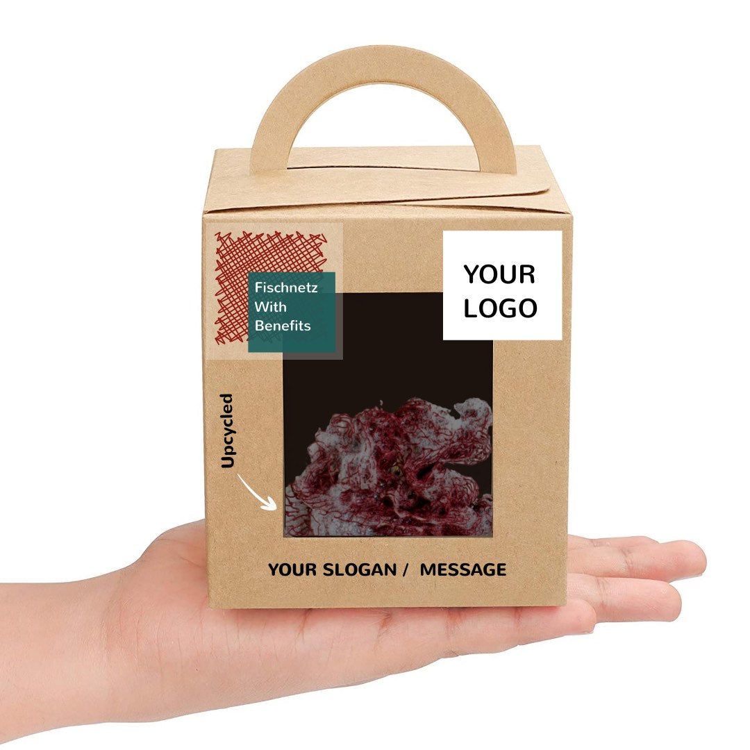 A box on a hand with a Fischnetz sponge alternative inside. The box is presented as a sustainable and eco-friendly corporate gift idea. The Fischnetz with Benefits logo is in one corner. The logo in the other corner says "your logo".