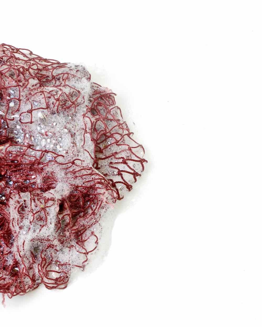 Red Fischnetz With Benefits as a reusable kitchen sponge alternative. The net is wet and has foam on it.